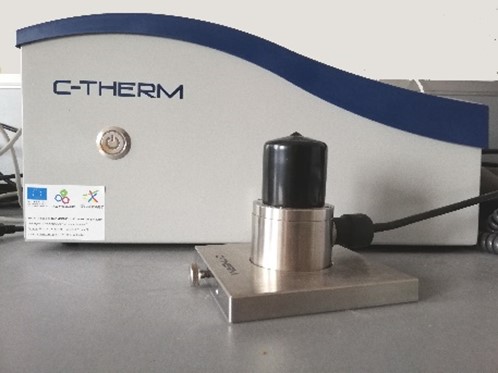 Benchtop analyser labelled C-THERM and a cylindrical sensor with a weight on a metal plate